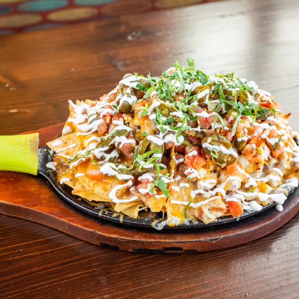 Tacos El Tio nachos with melted cheese, jalapeños, tomatoes, cilantro, and sour cream.
