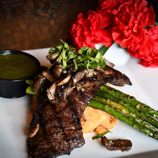 Grilled steak with mushrooms, cilantro, asparagus, mashed sweet potatoes, and green sauce.