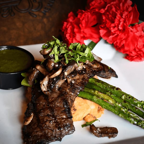 Grilled steak with mushrooms, cilantro, asparagus, mashed sweet potatoes, and green sauce.
